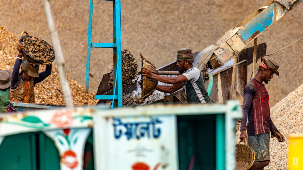 Workers carrying baskets of stone at the Jadukata River sand port near Tanguar Haor, Sunamganj, Bangladesh. Photo by Jaman | AsadSnapper.
